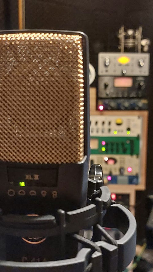 De 'Industry Standard' AKG C414 XLII microfoon met op de achtergrond de voorversterkers en channel-strips